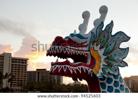 Dragon shaped head on traditional canoe on sand in Waikiki with hotels