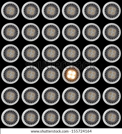 Many LED Light bulbs in pattern with only one illuminated and taken from above and isolated against black