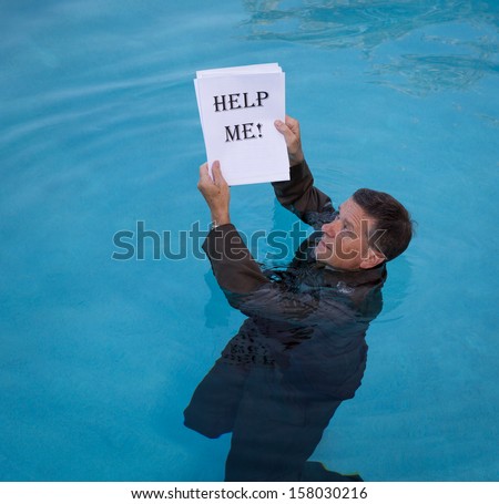 Senior caucasian businessman in suit up to neck in deep blue water worried about drowning in paperwork and holding help me document