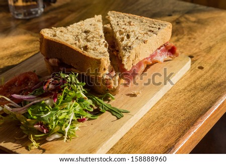 Bacon sandwich on thick wholemeal granary bread on wooden platter on pub lunch table