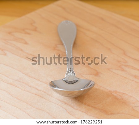 Decorated serving or dessert spoon in front view on wooden table or cutting board
