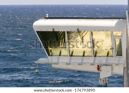 Cruise ship bridge cabin with the ships wake and surf reflected in the golden blinds on the windows as the ship sails to sea