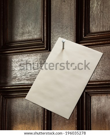 Envelope nailed to an old wooden door with a large nail in a threatening gesture from an angry person