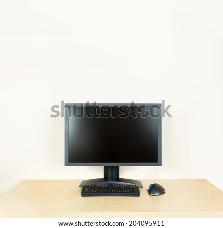Plain light colored wooden desk with computer monitor and keyboard to suggest calm, organization and meditation at work or in home office
