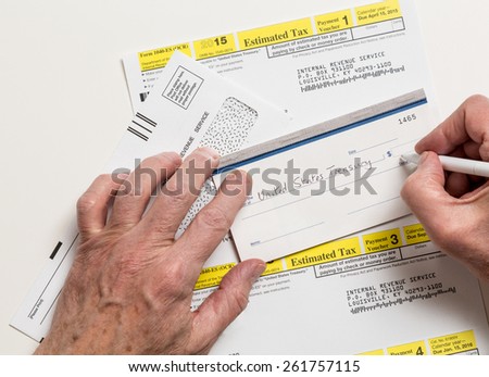 Male caucasian hands writing check to Internal revenue service IRS form 1040-ES for payment of estimated taxes in 2015