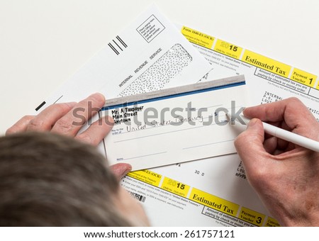 Male caucasian hands writing check to Internal revenue service IRS form 1040-ES for payment of estimated taxes in 2015
