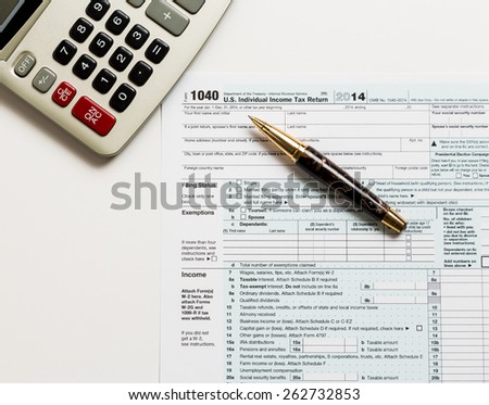 USA tax form 1040 for year 2014 with a pen and calculator illustrating completion of tax forms for the IRS