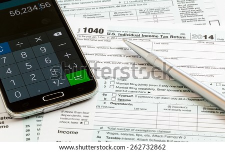 USA tax form 1040 for year 2014 with a pen and calculator app on smartphone illustrating completion of tax forms for the IRS
