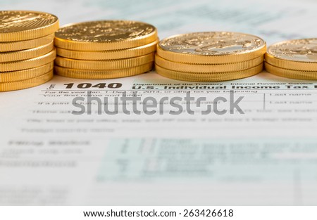 Solid gold eagle coins on USA tax form 1040 for year 2014  illustrating payment of taxes on forms for the IRS