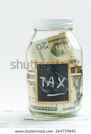 Glass jar on white background with black chalk label or panel and used for saving US dollar bills for income tax