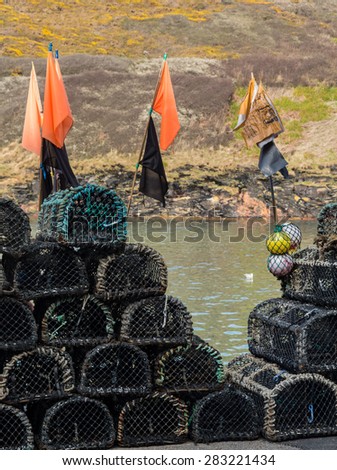 Rope and wooden frame lobster pot or trap stacked on stone wall of harbor in Boscastle, Cornwall, England UK