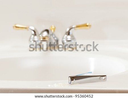 Finger nail clippings on bathroom sink with gold faucets or taps