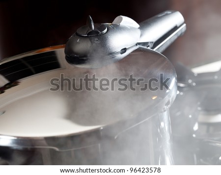 Steam escaping from lid of pressure cooker with reflection of modern kitchen