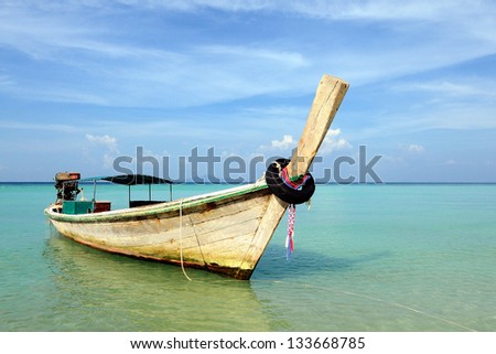 Long-tail boat in a bay against blue sky background