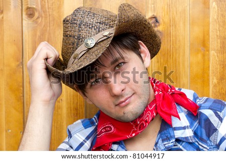 Portrait of man wearing cowboy hat, silk scarf, and checked shirt. Photo is taken in Calgary during Stampede