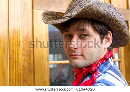 Portrait of man wearing cowboy hat, silk scarf, and checked shirt. Photo is taken in Calgary during Stampede