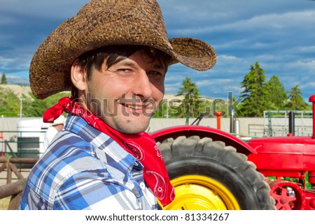 Portrait of smiling tractor driver wearing cowboy hat, silk scarf, and checked shirt. Photo is taken during Calgary Stampede 2011