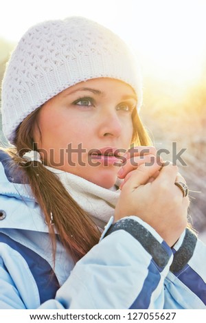 young adult woman are in warm clothes,outdoor in winter, sunset is on the background/ sunset portrait