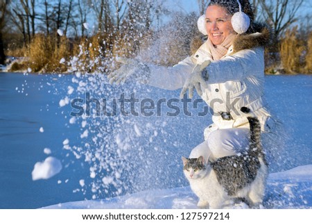 beautiful girl playing with a cat, and throw snow in to the air/Woman playing with cat