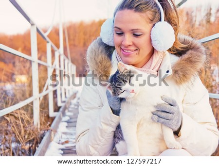 Beautiful brown hair woman playing with a domestic cat, winter outdoor scene/Woman playing with cat 2