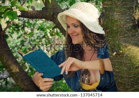 Reading in the garden / Young woman reading a book in the garden