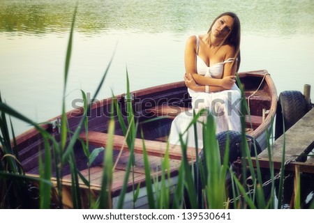 Lonely as a boat / Beautiful young sad woman sitting in a boat