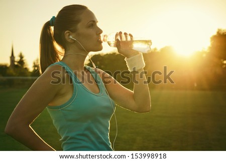 Doing Sport in the sunset Young woman drinking water after run Doing Sport in the sunset Young woman drinking water after run