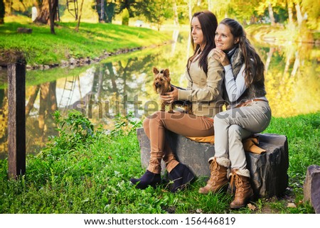 Friends in the park  / Beautiful girlfriends are in the park with their dog, in autumn