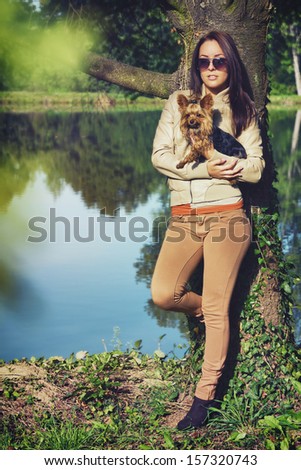 Friends in the park / Beautiful young woman standing in a park with her dog