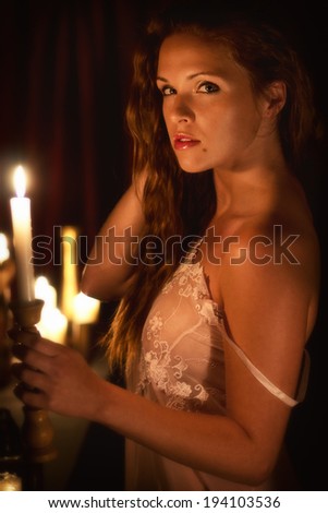 Woman with a candle / Beautiful young woman in a dark with a candle