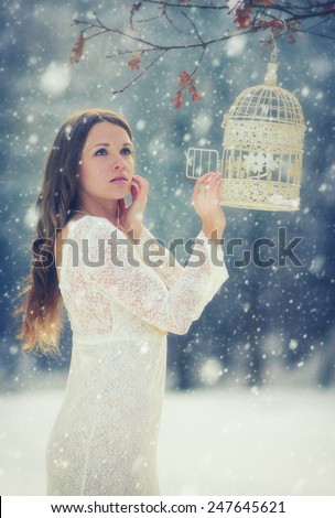 The missing bird / Mystic young women in snowfall with a bird cage