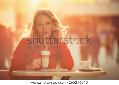 Young woman make a call during her coffee break, in the sunset  / Vintage style photo with custom white balance, color filters, vignette and light glow effects, and fine film noise added