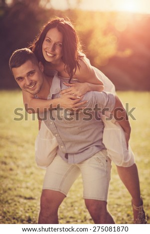 Attractive Couple Enjoying Romantic Sunset in the Countryside / Vintage style photo with custom white balance, color filters, lens flare, and relatively \