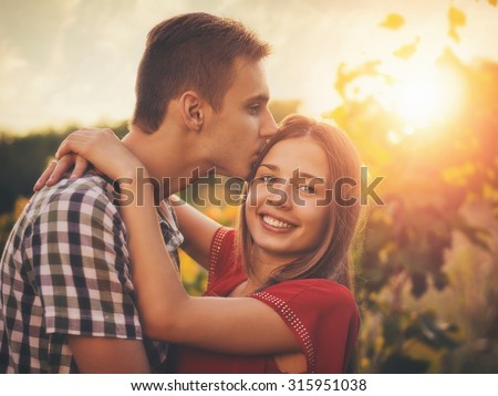 Attractive couple enjoying romantic date in the Countryside, sunset in the background / Vintage style photo with custom white balance, color filters, and some fine film grain added