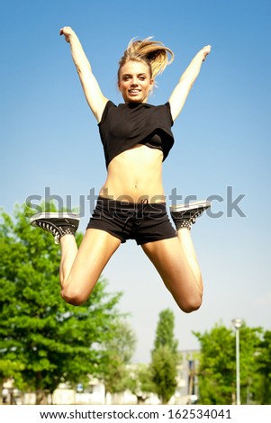 Young cute happy woman jumping in freedom in city park