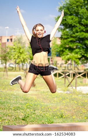 Young cute happy woman jumping in freedom in city park