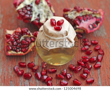 Pomegranate seed oil in bottle on red wooden background, close-up
