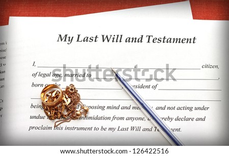 Last Will and Testament form with gold jewelry on red background, close-up