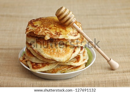 pancakes with honey and wooden dipper on canvas background, close-up