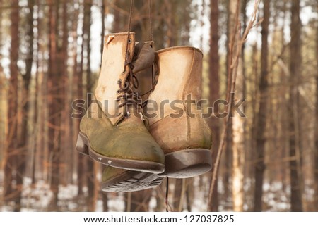 Old worn boots hanging on a tree in an winter forest