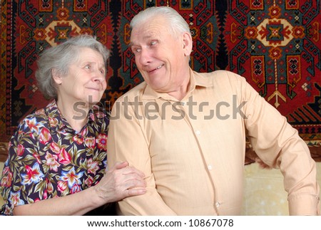 Seventy year old couple smiling at home on sofa
