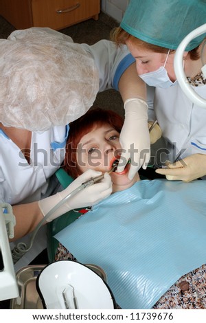 Woman with open mouth look at camera. Doctor to drill a tooth. Nurse to help a doctor.