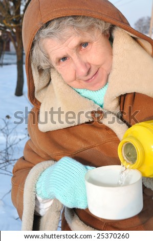 happy granny with thermos on winter background looking at camera