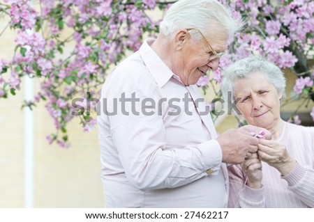 pretty old pair hold in hands small flower; outddor