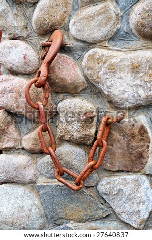 close up wall from stone and steel hook on chain