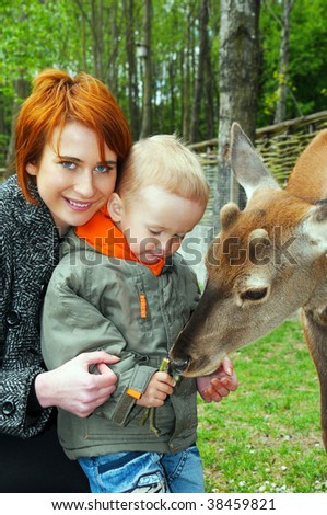 Young mother and son pet a deer