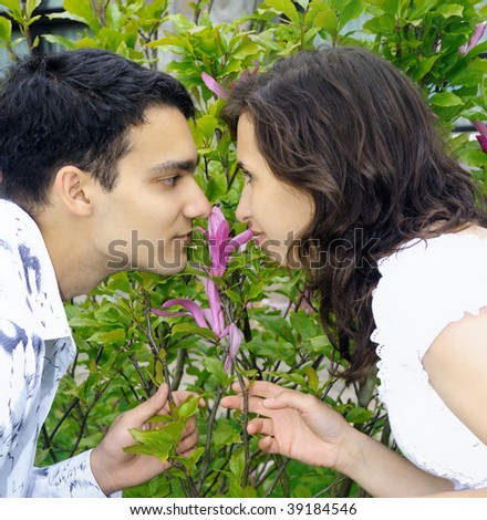 Beautiful young couple outdoors smells a flower