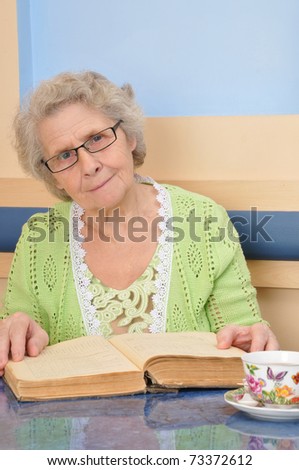 elderly woman with the book looks into the camera