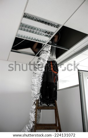 worker raises isolated flexible hose for ventilation
