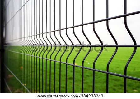 Metal fence wire, grass and sky in the background